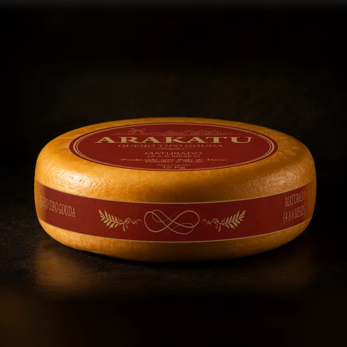 Roda inteira de queijo tipo Gouda Arakatu Maturado, rótulo vermelho, sobre fundo escuro